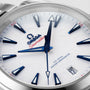 Close-up of an OMEGA Seamaster Aqua Terra 150M watch face featuring blue hour markers and hands, a white textured dial, date window at 6 o’clock, and powered by the precise calibre 8900 movement.
