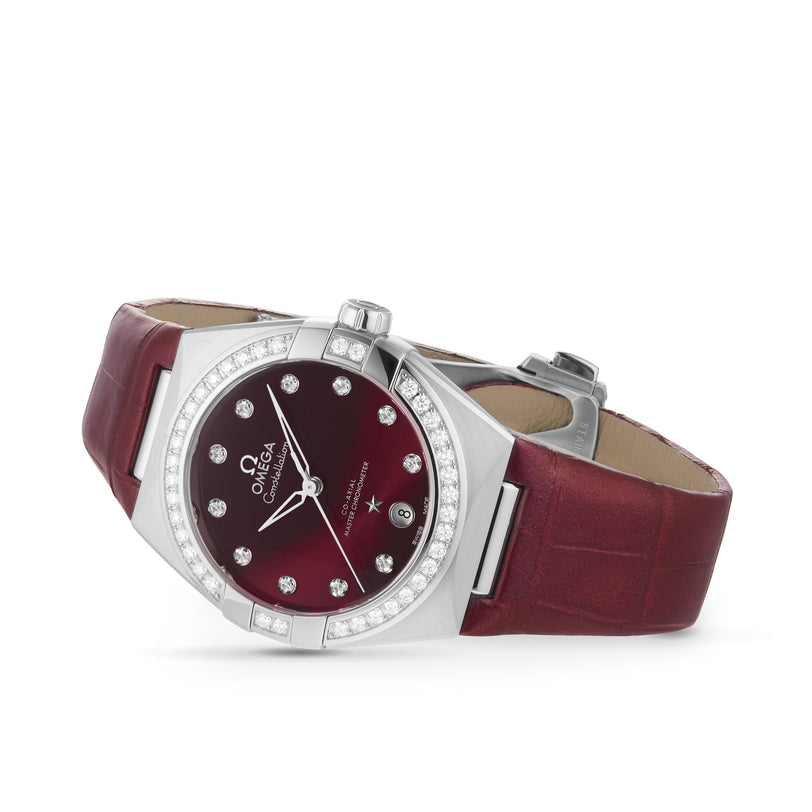 The OMEGA Constellation is a luxury wristwatch with a burgundy leather strap, diamond-set bezel, burgundy dial with diamond hour markers and the OMEGA logo, powered by a Master Chronometer certified 8800 calibre movement.