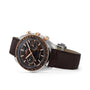 The OMEGA Speedmaster Moonwatch Co-Axial Chronograph features a brown dial, chronograph functions, rose gold accents, a realistic moonphase display, and a 42.5 mm stainless steel and 18K Sedna™ gold case shown at an angle.