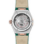 Back view of the OMEGA Constellation showing its exposed mechanical movement, engraved details, and green and cream leather strap enhanced with luxurious 18K Sedna™ gold accents.