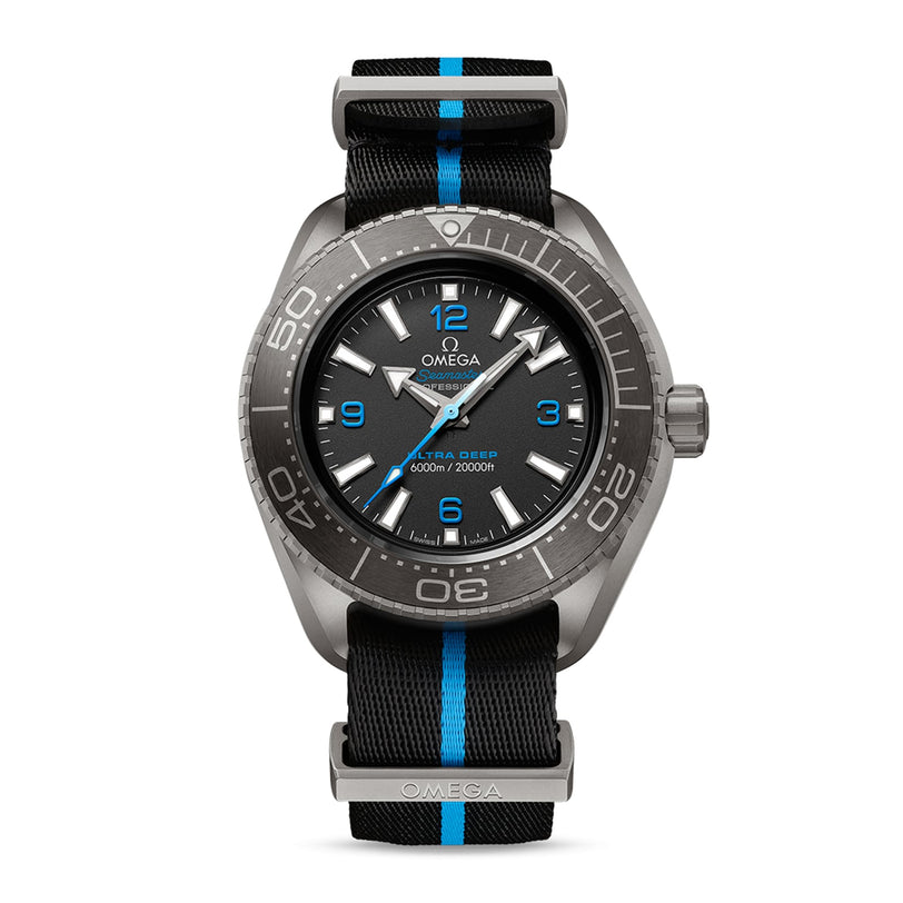 The OMEGA Seamaster Planet Ocean 6000M dive watch boasts a black dial with blue accents, a black and blue striped NATO strap, and a remarkable 6000m/20000ft depth rating on the face.