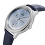 A close-up of the OMEGA De Ville Prestige wristwatch, featuring a stainless steel case, blue leather strap, light blue dial with Roman numerals, and a date display at 6 o’clock.
