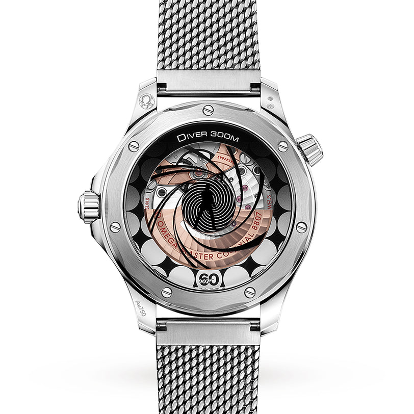 A close-up of the OMEGA Seamaster Diver 300M James Bond 60th Anniversary shows its detailed mechanical movement through a sapphire case back, paired with a metal mesh band and inspired by the iconic 007 legacy.