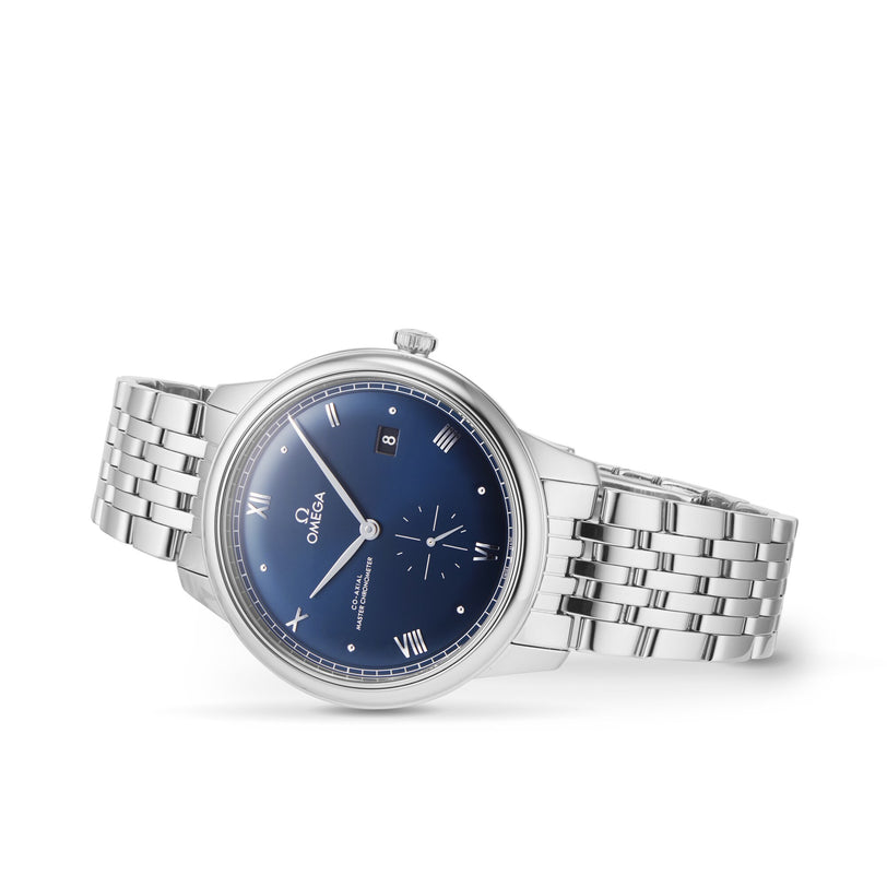 The OMEGA De Ville Prestige wristwatch features a blue dial with Roman numerals, date window, silver link bracelet, and Master Co-Axial Calibre 8802, showcased against a white background.