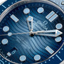 Close-up of the OMEGA Seamaster Diver 300M Summer Blue watch, featuring its blue wavy Master Chronometer dial, hands, indices, and a date window at 6 oclock.