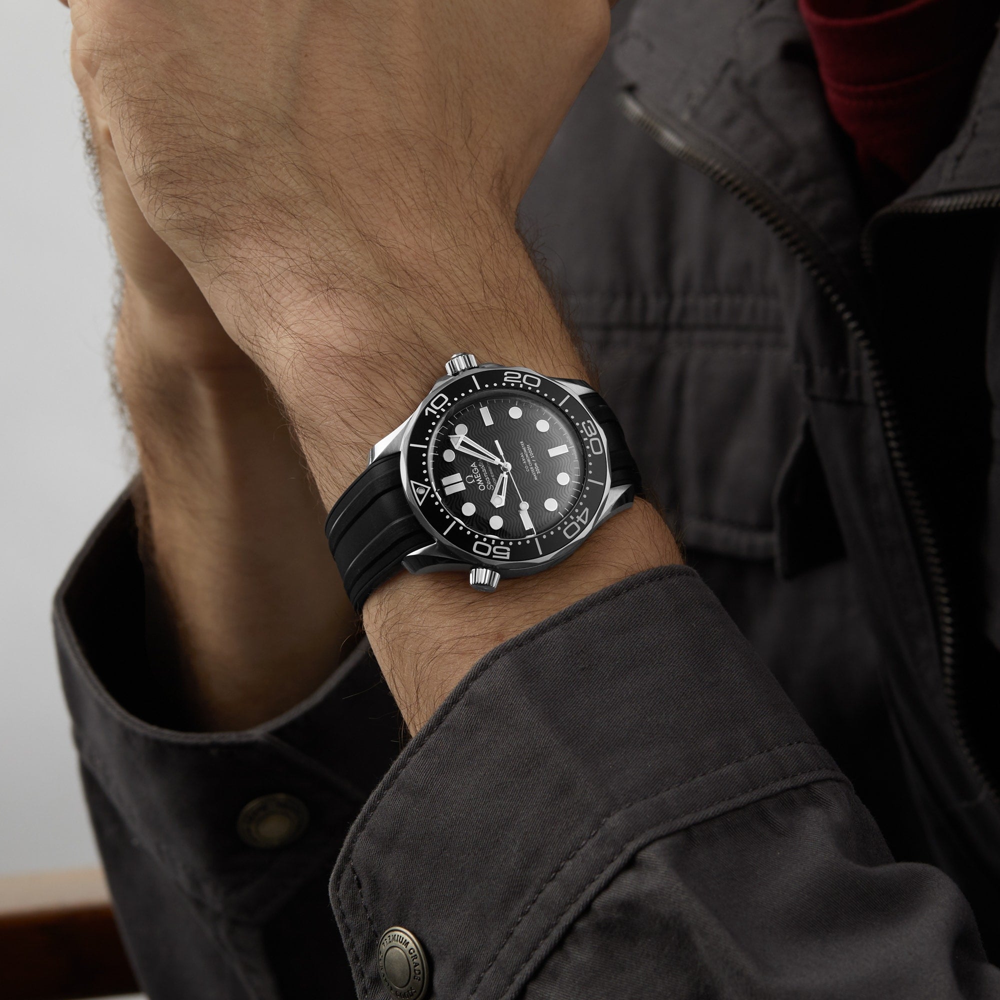 An individual wearing the OMEGA Seamaster Diver 300M with a stainless steel case and black rubber strap, paired with a dark jacket, draws attention to the watch’s striking dial and bezel.