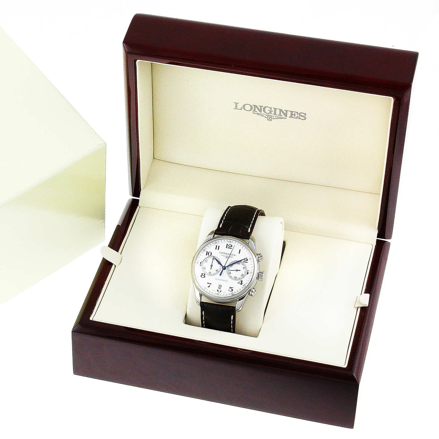 The Longines Master Collection Chronograph wristwatch, with blued steel hands and a black leather strap, is displayed in an open cream and brown presentation box, exuding classic elegance.