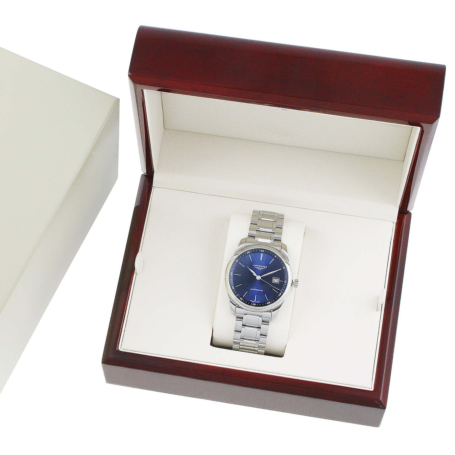 The Longines Master Collection wristwatch, with a silver band and blue face, is presented in an open wooden display box beside a cream outer box.
