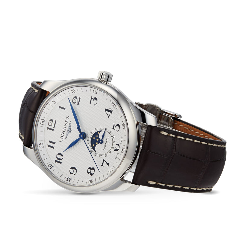The Longines Master Collection Moonphase is a silver wristwatch with a white face, blue hands, black Arabic numerals, moonphase subdial, and brown leather strap with white stitching—a stylish tribute to vintage timepieces.