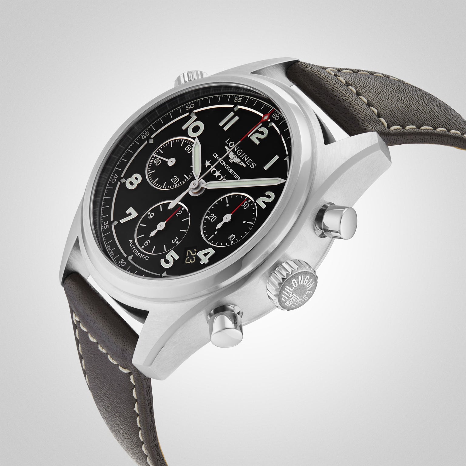 The Longines Spirit Chronograph wristwatch features a black dial with three subdials, grey leather strap, and L688.4 calibre movement, displayed against a light grey background.