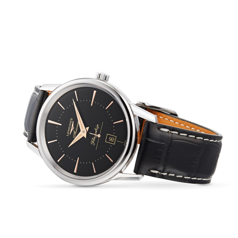 A silver Longines Flagship Heritage wristwatch with a black dial, black leather strap, date display set to 16, and silver hour markers and hands coated with Swiss Super-LumiNova for enhanced visibility.