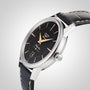 A close-up of a Longines Flagship Heritage wristwatch featuring a black dial, gold hour markers with Swiss Super-LumiNova, date display, and a black leather strap.