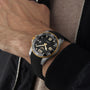 Wearing a Longines HydroConquest watch with black strap and dial, paired with a beige sweater and black jacket.