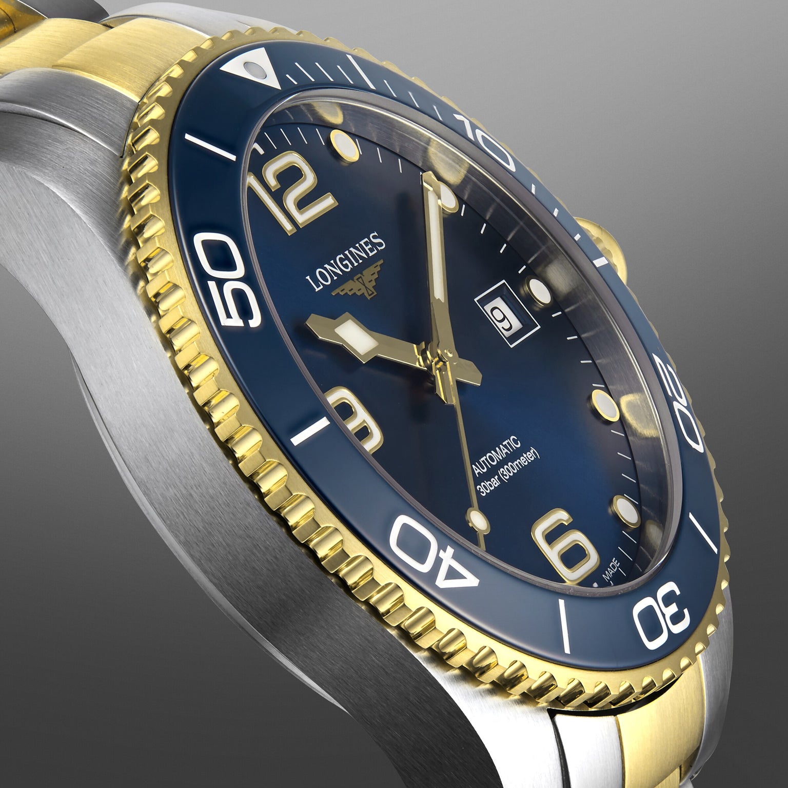 Close-up of a Longines HydroConquest watch featuring a two-tone design, blue dial, gold bezel, luminous markers, automatic movement, and date window.