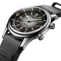 A close-up of the Longines Legend Diver watch, showcasing its L888 calibre movement, black dial with luminous markers, dual crowns, and a green fabric strap.