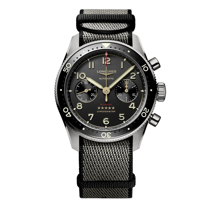 The Longines Spirit Flyback Titanium is a pilot watch with a titanium chronograph case, black dial with two subdials, black bezel, and a black and gray fabric strap.