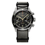 The Longines Spirit Flyback Titanium is a pilot watch with a titanium chronograph case, black dial with two subdials, black bezel, and a black and gray fabric strap.