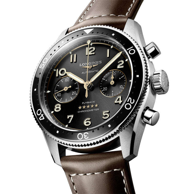 A close-up of the Longines Spirit Flyback, featuring a black dial, silver case, three subdials, brown leather strap, and powered by an automatic movement.