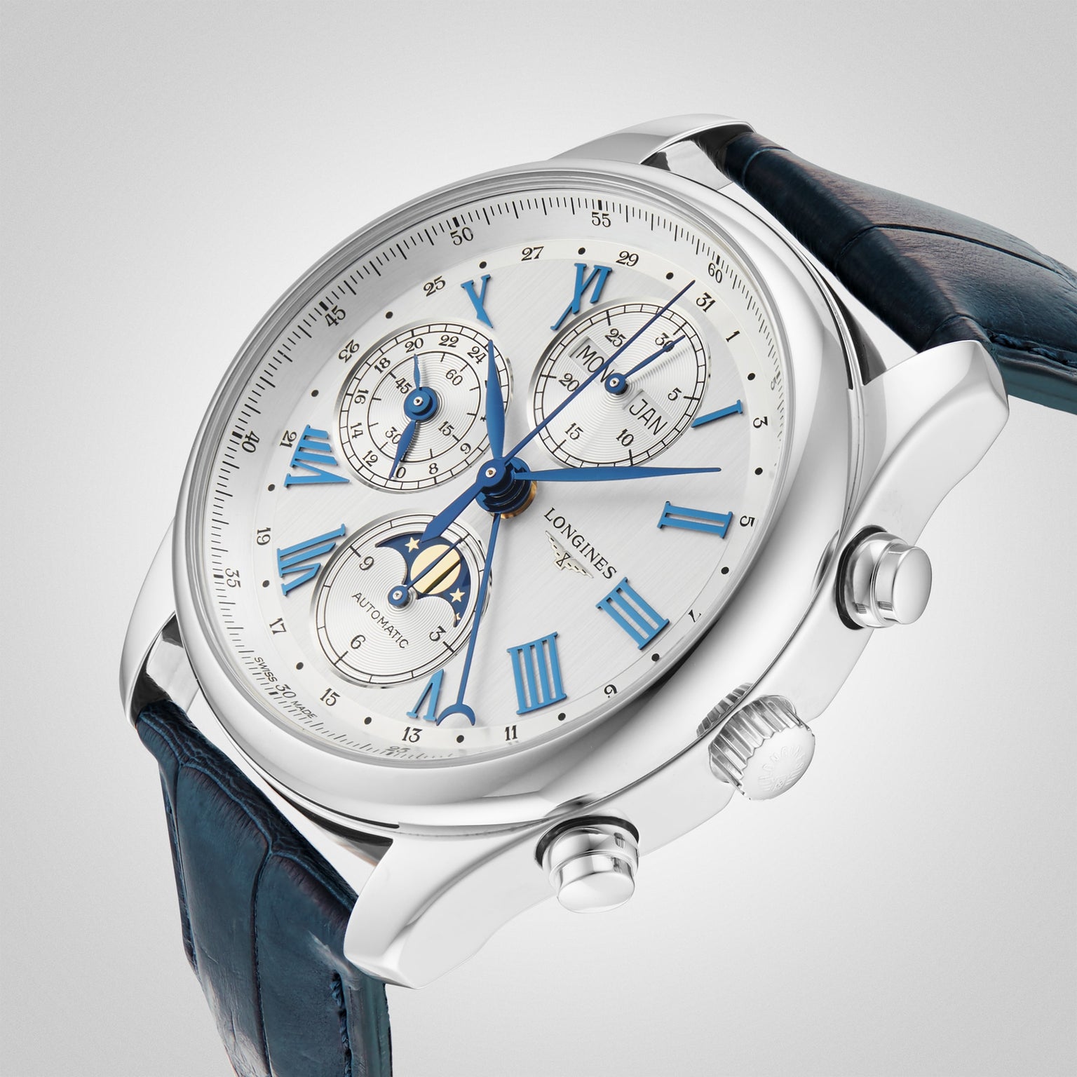 The Longines Master Collection Chrono Moonphase features a silver case, white dial with blue Roman numerals, three chronograph subdials, two pushers, and a blue leather strap, shown against a plain gray background.