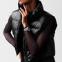 A person in a black puffer vest over a sheer long-sleeve top poses with one hand near their face, showcasing the Longines Legend Diver watch.