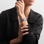 A person in a black long-sleeve shirt wears a Longines Mini DolceVita with a rectangular face and stainless steel bracelet on their left wrist.