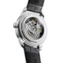 The image shows the back of the Longines Conquest Heritage Central Power Reserve, featuring a silver case, black leather strap, and a transparent case back revealing its automatic movement and internal gears.