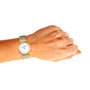A left hand wears a Longines La Grande Classique de LONGINES wristwatch in silver and gold set to 10:10, displayed against a white background, exemplifying elegance and sophistication.