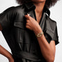A person wearing a short-sleeve black belted shirt dress adjusts their collar while sporting the Longines La Grande Classique de LONGINES gold wristwatch.