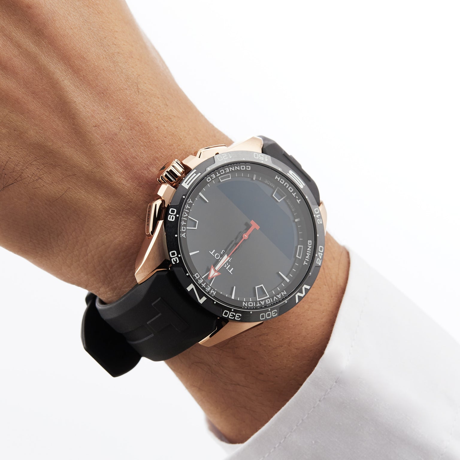 A person wears a Tissot T-Touch Connect Solar wristwatch with a black rubber strap, antimagnetic titanium case, and solar power reserve, paired with a white cuffed shirt.