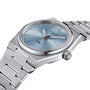 The Tissot PRX features a stainless steel case, blue dial, silver markers, and a date at 3 o’clock. Shown at an angle, it showcases its 1970s-inspired design and Swiss quartz precision.
