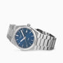 The Tissot PRX features a stainless steel case, blue dial with silver hour markers, Swiss quartz movement, date window at 3 o’clock, and a linked metal bracelet.
