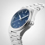 The Tissot PRX features a stainless steel case, Swiss quartz movement, blue dial with silver hour markers, date display, and metal bracelet, shown on a light background.