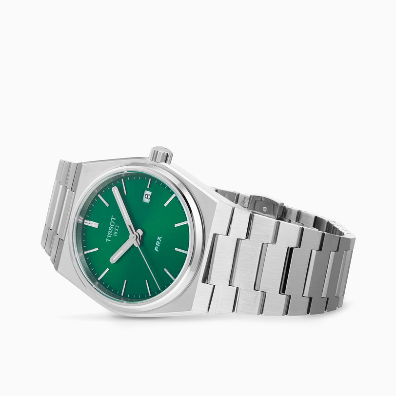 The Tissot PRX features a stainless steel case, green dial with silver hour markers and date window, set on a metal link bracelet and shown against a plain white background.