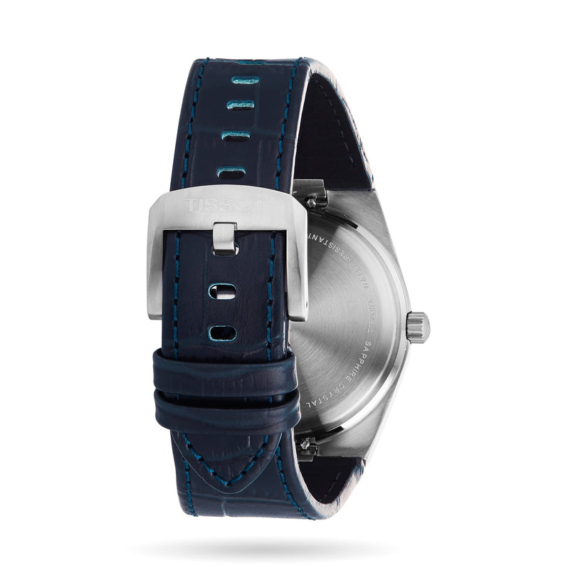 A close-up of the Tissot PRX watch’s back highlights its stainless steel case, blue leather strap, and silver buckle—a modern tribute to classic 1970s design.