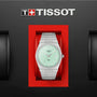 The Tissot PRX stainless steel watch with a mint green dial features its sleek design in a red case, displayed below the Tissot logo on a black background.