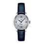 The Tissot Le Locle Automatic 20th Anniversary watch features a silver case, white textured dial, blue Roman numerals and hands, automatic movement, date display at 3 o’clock, and a dark blue leather strap.