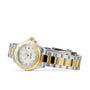 The TAG Heuer Aquaracer Date, a two-tone wristwatch in stainless steel and 18K gold with a white dial, date display, and metal link bracelet, is elegantly displayed on its side against a white background.
