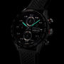 Close-up of the TAG Heuer Carrera Chronograph, featuring a black dial, illuminated hands, tachymeter bezel, and black perforated rubber strap—powered for endurance.