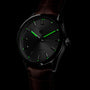 The TAG Heuer Carrera Day-Date features a brown alligator leather strap, black dial with luminous green markers and hands, Calibre 5 movement, and displays both day and date.