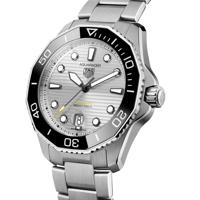 The TAG Heuer Aquaracer Professional 300 Date is a silver diver’s watch with a black bezel, silver dial, yellow seconds hand, and stainless steel bracelet.
