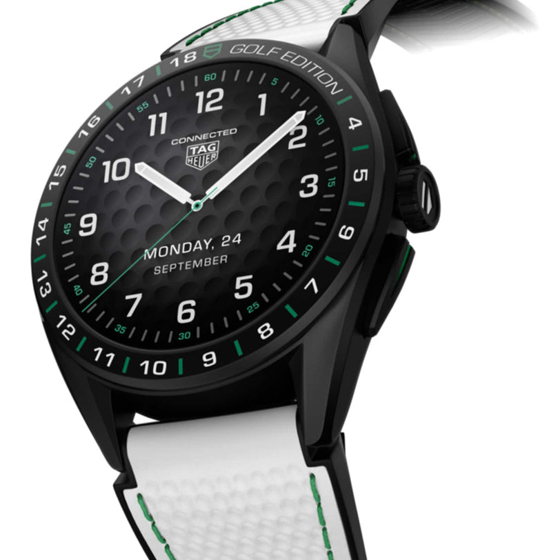 The TAG Heuer Connected Calibre E4 Golf Edition smartwatch features a black, round face, ultra-light Grade 2 titanium case, and a white strap with green accents, plus a digital display for date and day.