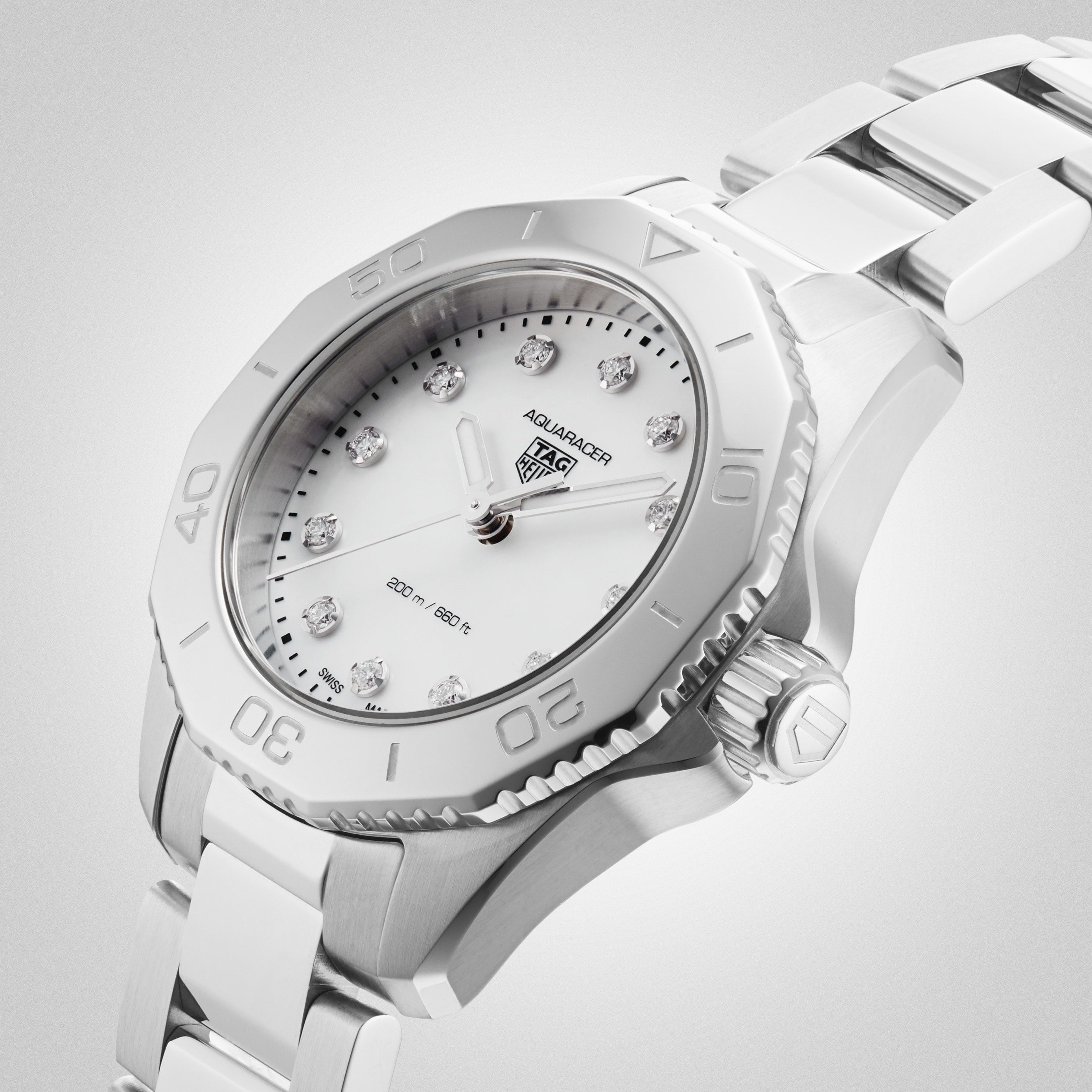 The TAG Heuer Aquaracer Professional 200 sports watch features a stainless steel case, white dial with diamond hour markers, and matching bracelet, shown at an angle on a light gradient background.