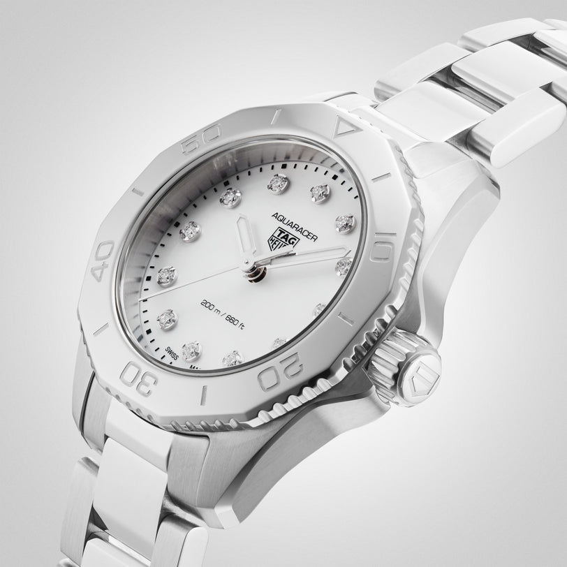 The TAG Heuer Aquaracer Professional 200 sports watch features a stainless steel case, white dial with diamond hour markers, and matching bracelet, shown at an angle on a light gradient background.