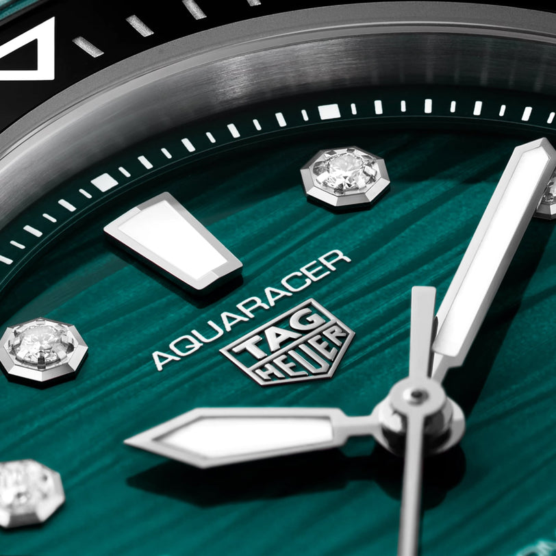 Close-up of the TAG Heuer Aquaracer Professional 300 Date watch face with a green background, silver hands, silver hour markers, and diamond accents.
