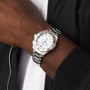 A person wearing a TAG Heuer Aquaracer Professional 200 Chronograph with a silver case, white dial, and black accents, dressed in a black jacket over a white shirt.