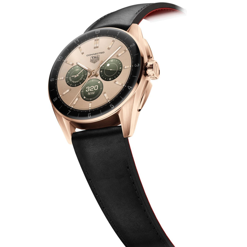 A TAG Heuer Connected Calibre E4 Golden Bright Edition luxury watch with a black leather strap and digital display is shown at an angle on a white background.