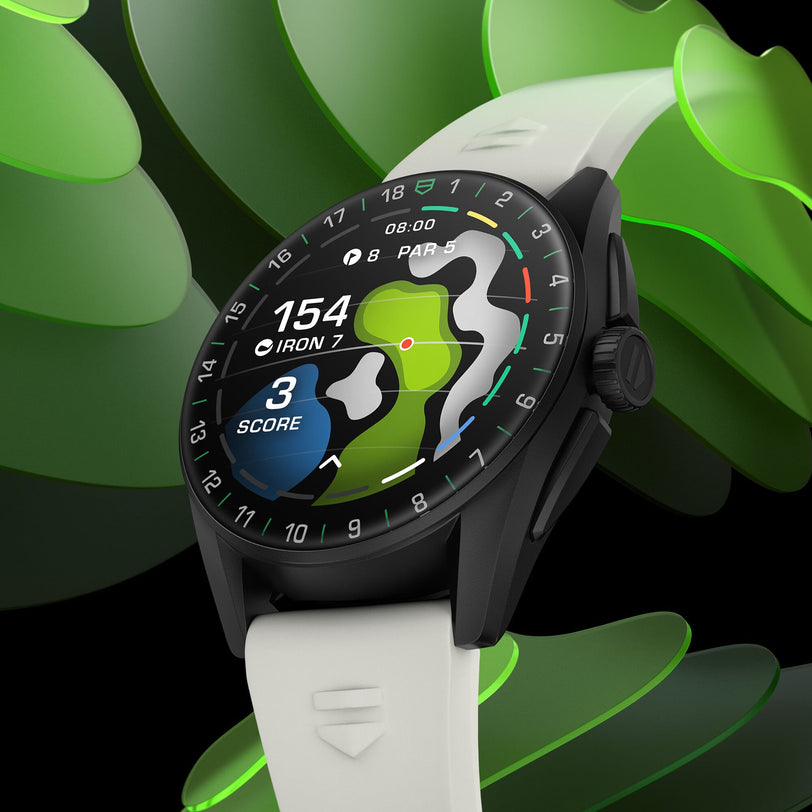 A TAG Heuer Connected Calibre E4 Golf Edition smartwatch with a white strap and ultra-light Grade 2 titanium shows a golf course map, hole data, shot distance, and score on its round screen against a green abstract background.