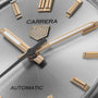 Close-up of the TAG Heuer Carrera Date watch face, highlighting gold hands and markers on a silver background—a refined display of endurance and elegance.