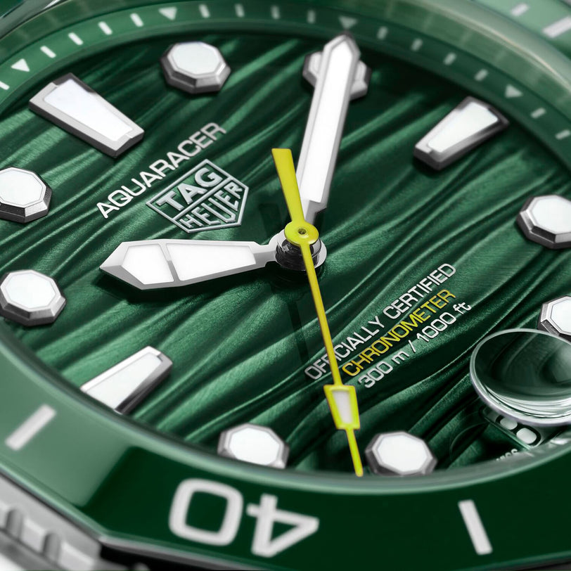 Close-up of a green TAG Heuer Aquaracer Professional 300 Date watch face with a green ceramic bezel, showing the hands, markers, logo, and Officially Certified Chronometer text.