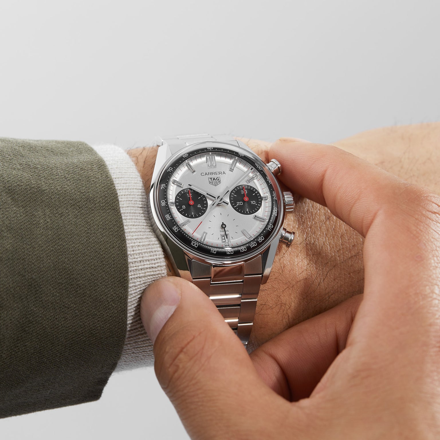 Someone wears a TAG Heuer Carrera Chronograph watch in silver and adjusts its crown.